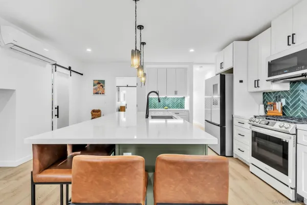 a kitchen with stainless steel appliances granite countertop a refrigerator a stove and white cabinets with wooden floors