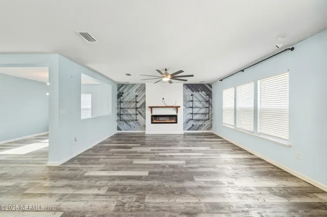 a view of empty room with wooden floor and fan