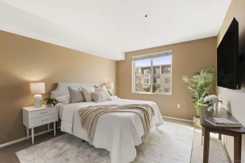 a bedroom with a bed table chair and a flat screen tv