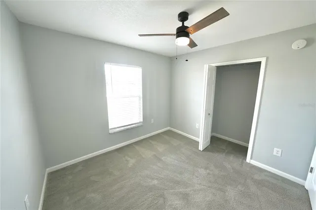 an empty room with ceiling fan and window