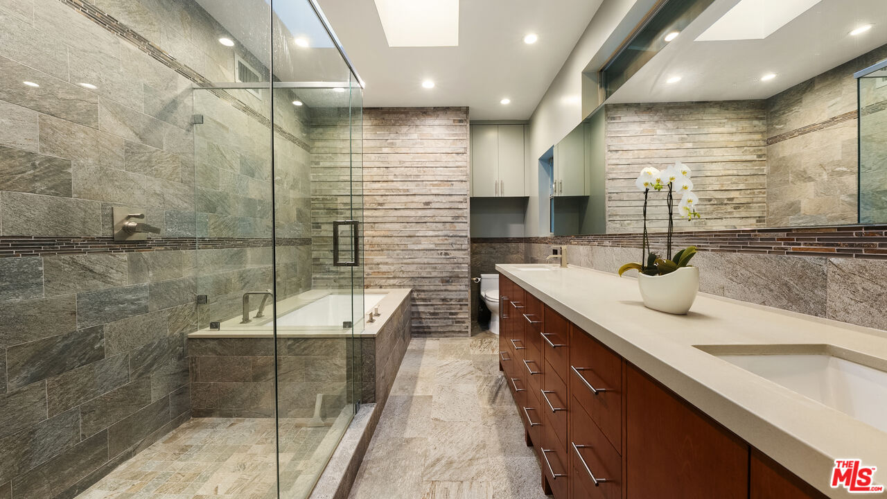 13044 Sky Valley Road Los Angeles, CA 90049 - Photo 22 of 29 a bathroom with a double vanity sink a mirror and shower
