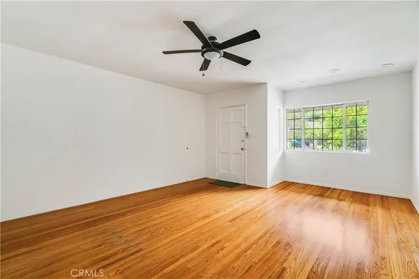 an empty room with wooden floor fan and windows