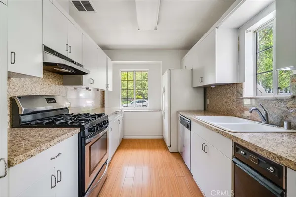 a kitchen with a sink stove top oven and cabinets