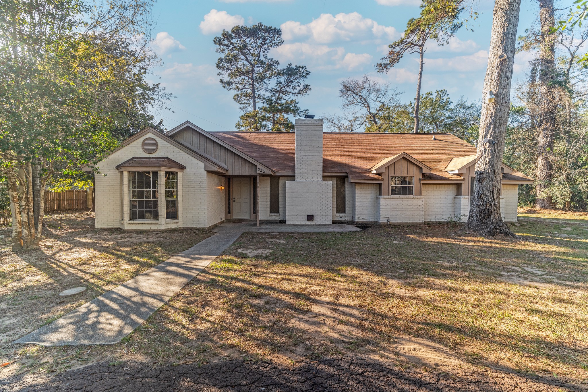 235 Beech Road Conroe, TX 77304 - Photo 1 of 6 a view of a white house next to a yard with big trees