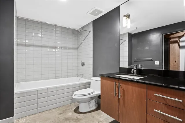 a bathroom with a granite countertop sink toilet mirror and bathtub