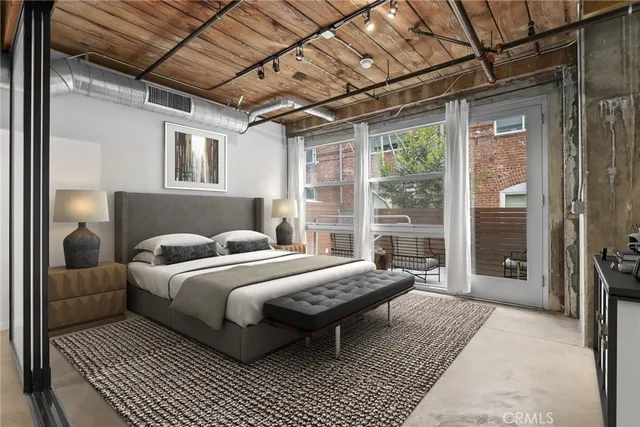 a bedroom with a bed wooden floor and next to a window