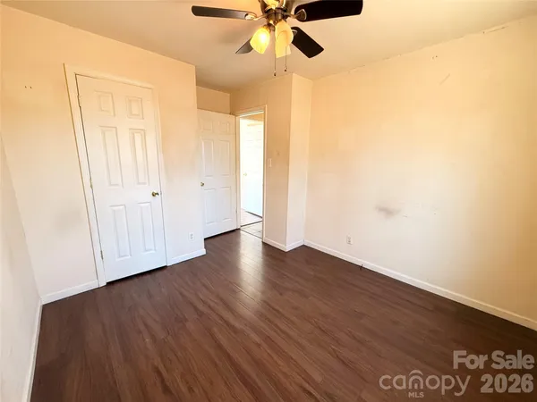 an empty room with wooden floor fan and windows