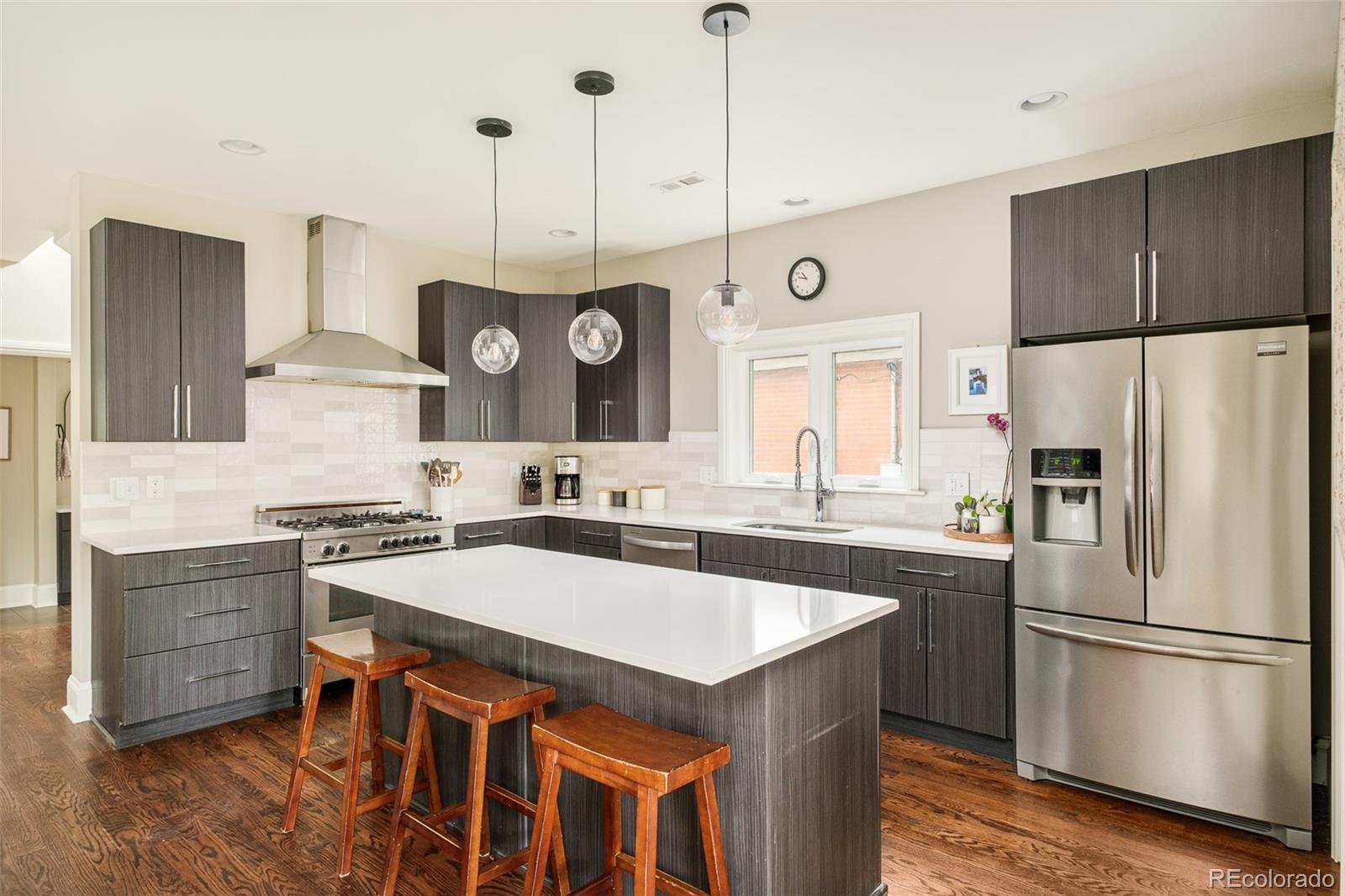 3864 Osceola Street Denver, CO 80212 - Photo 17 of 43 a kitchen with stainless steel appliances granite countertop a sink a stove a refrigerator and island with wooden floor