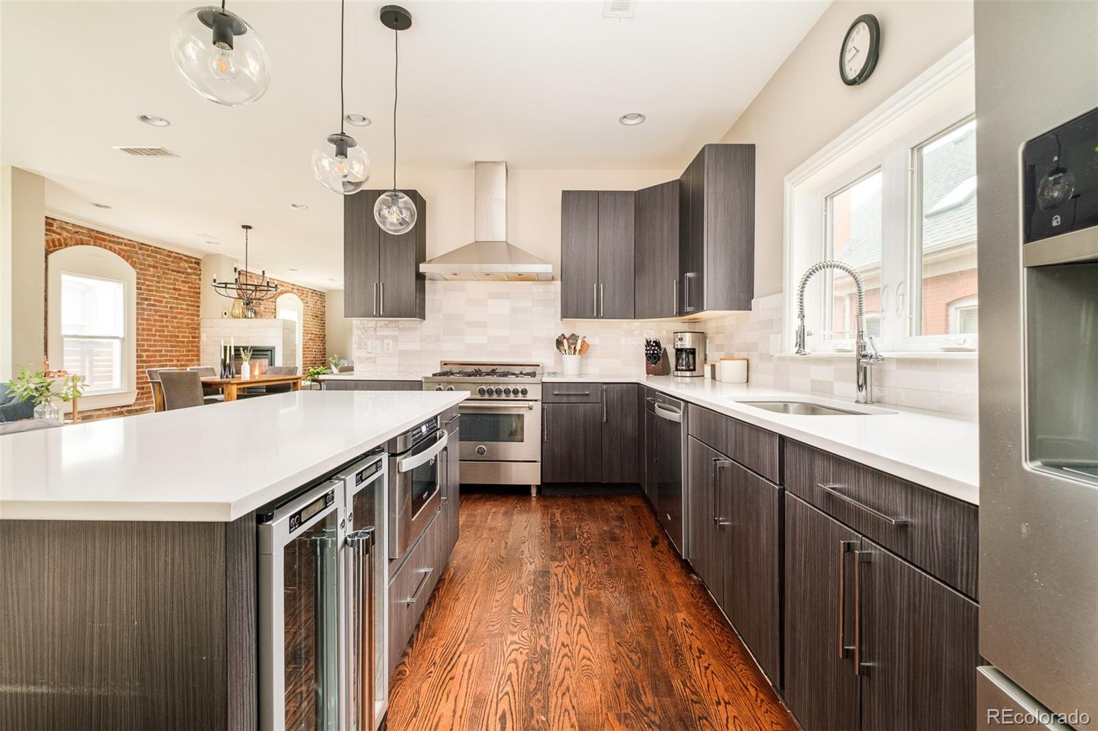 3864 Osceola Street Denver, CO 80212 - Photo 19 of 43 a kitchen with stainless steel appliances a sink dishwasher a stove a refrigerator and a dining table with wooden floor