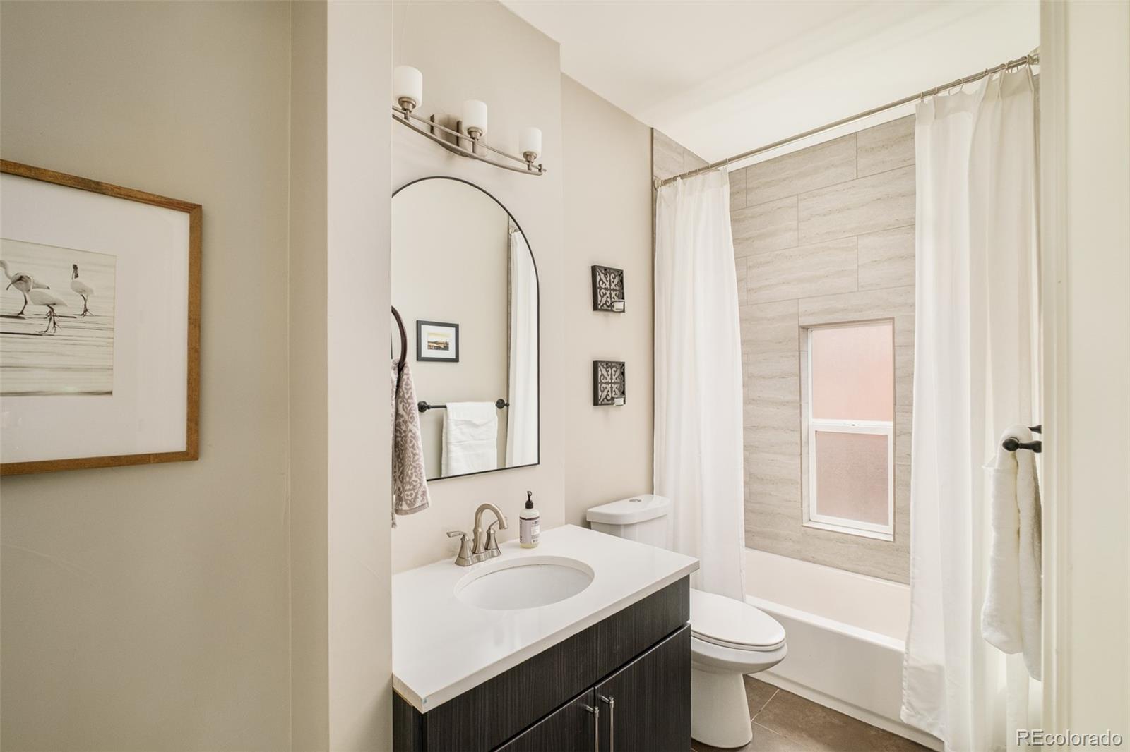 3864 Osceola Street Denver, CO 80212 - Photo 21 of 43 a bathroom with a granite countertop sink a toilet and a mirror