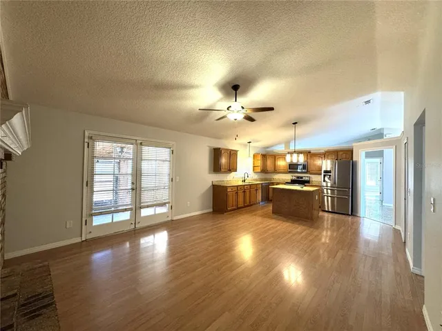 a view of a kitchen with a stove wooden cabinets and a living room