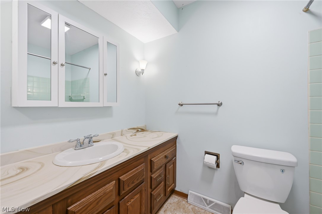 1501 Ohltown McDonald Road Mineral Ridge, OH 44440 - Photo 23 of 32 Bathroom featuring a wood vanity with an integrated sink, patterned countertop, and a mirrored medicine cabinet