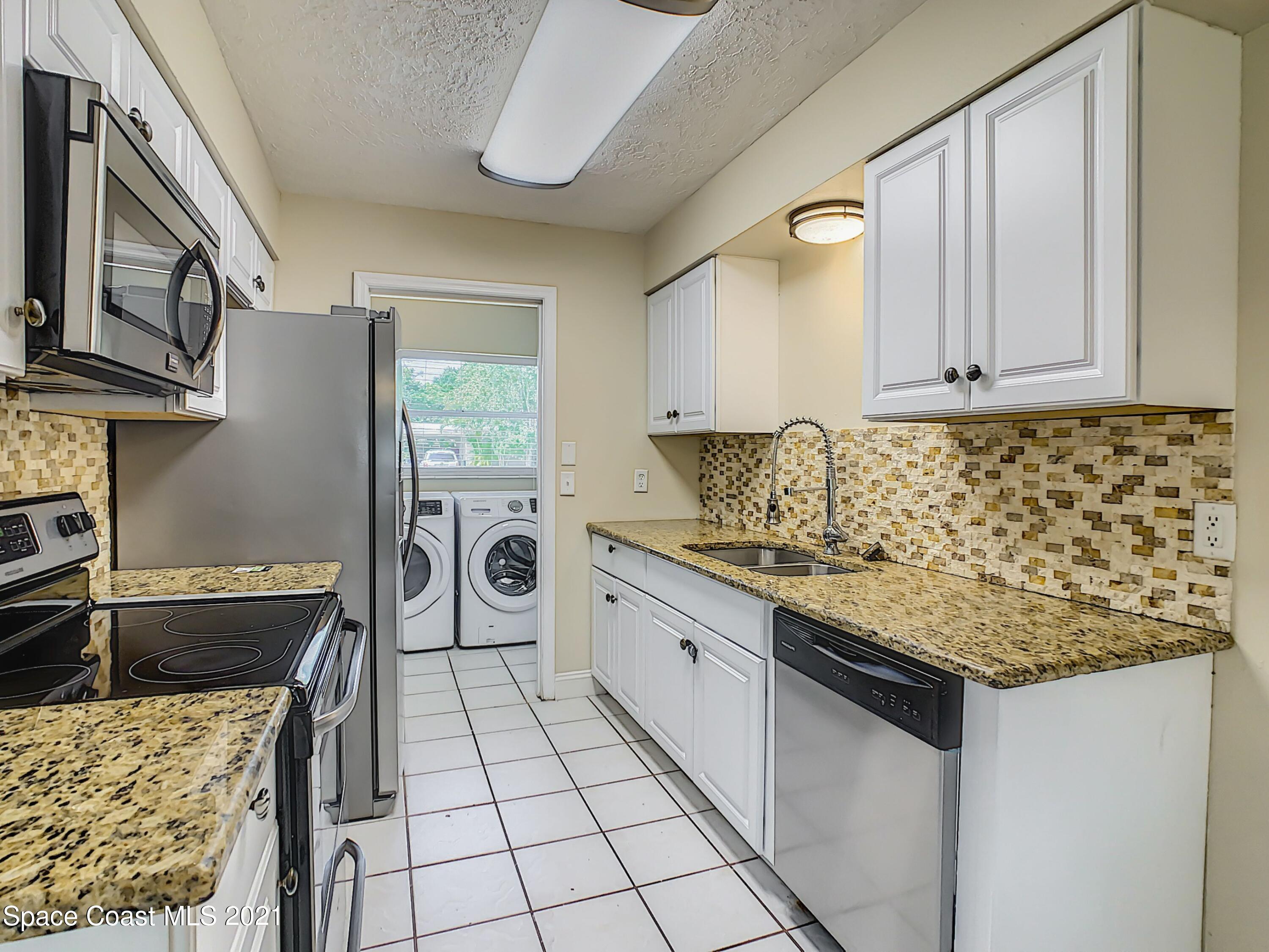 1091 Madrid Road Rockledge, FL 32955 - Photo 11 of 33 a kitchen with stainless steel appliances granite countertop a stove sink and cabinets
