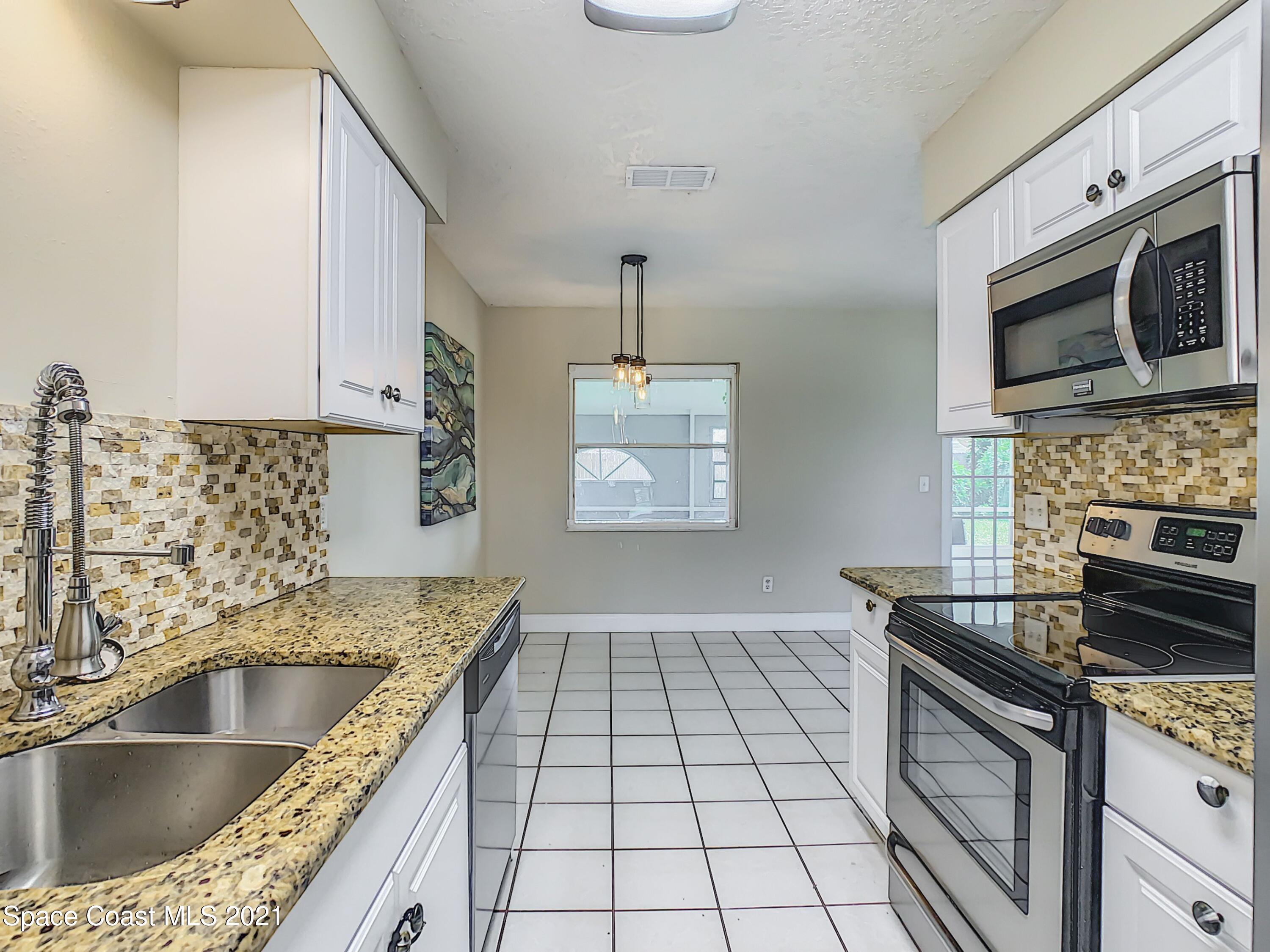 1091 Madrid Road Rockledge, FL 32955 - Photo 14 of 33 a kitchen with granite countertop a sink stove and cabinets