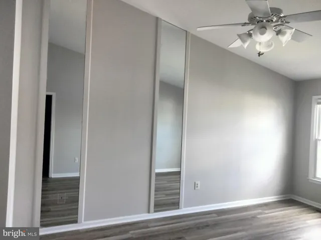 an empty room with wooden floor and ceiling fan