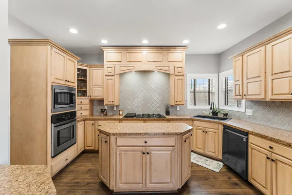 a kitchen with granite countertop a sink stainless steel appliances and cabinets