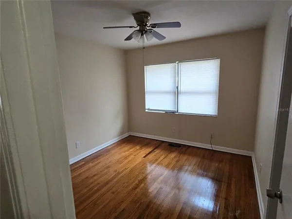 a view of an empty room with window and wooden floor