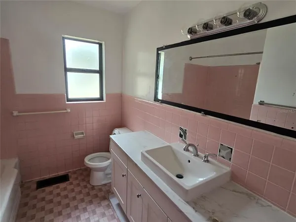 a bathroom with a sink mirror toilet and window