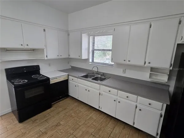 a kitchen with granite countertop white cabinets and black appliances