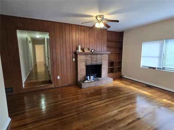 a view of an empty room with wooden floor fireplace and a window
