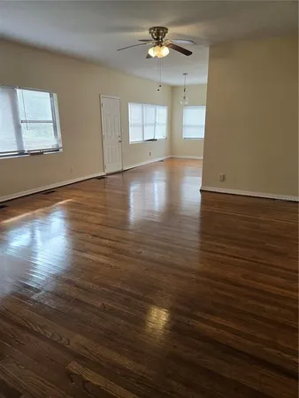 a view of empty room with wooden floor and fan
