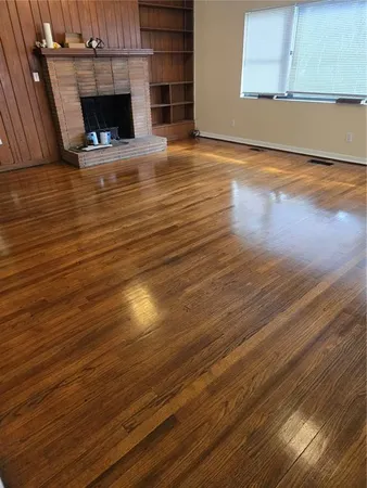 a view of an empty room with wooden floor and a fireplace