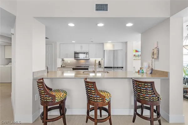 a kitchen with stainless steel appliances a dining table chairs and white cabinets