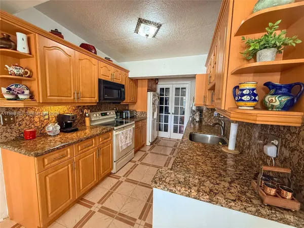 a kitchen with stainless steel appliances granite countertop a stove top oven a sink a dining table and chairs with wooden floor