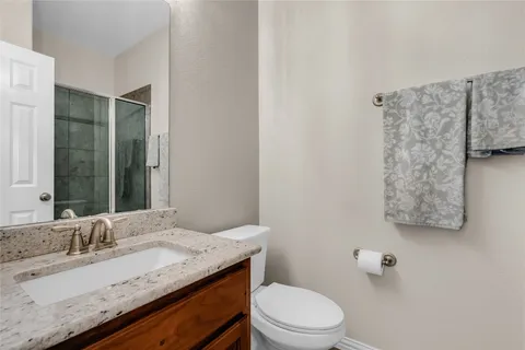 a bathroom with a granite countertop sink a toilet and a mirror