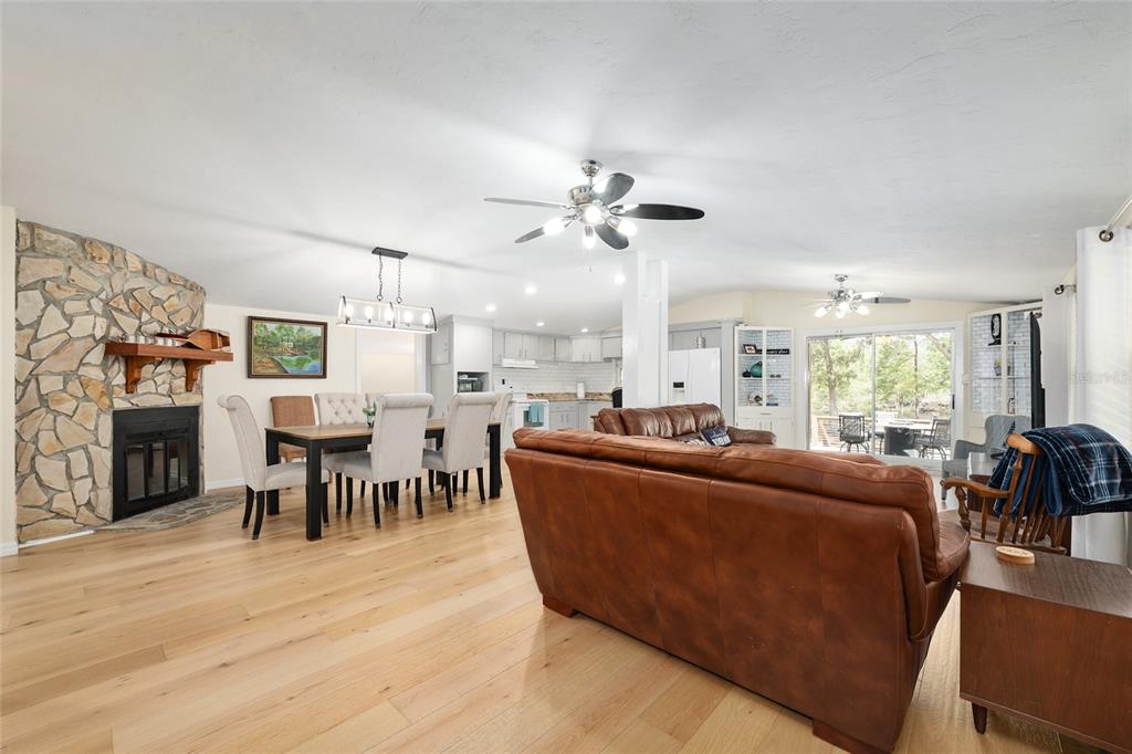 7870 Southwest 25th Place Bell, FL 32619 - Photo 65 of 99 a living room with furniture a fireplace and a dining table with wooden floor