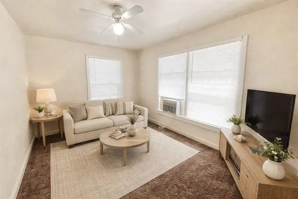a living room with furniture a flat screen tv and a large window
