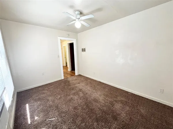 an empty room with a ceiling fan and carpet
