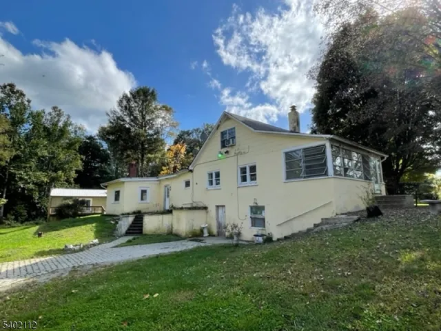 a view of a white house with a big yard and large trees