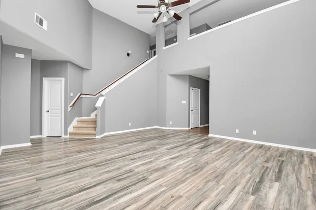 a view of an empty room with wooden floor and stairs