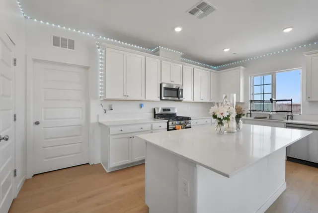 a kitchen with kitchen island a white counter top space cabinets and stainless steel appliances