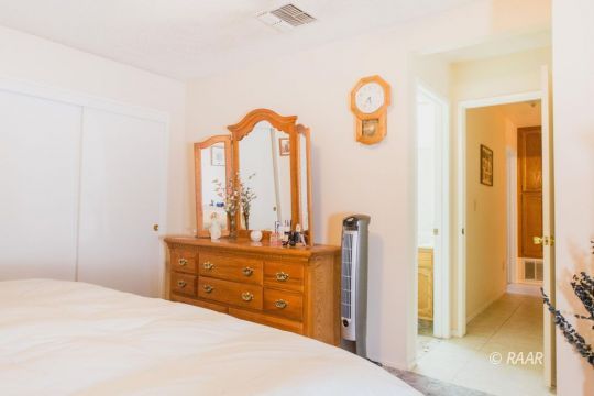 717 Ginger Avenue Ridgecrest, CA 93555 - Photo 15 of 28 a bedroom with a bed and a dresser with mirror