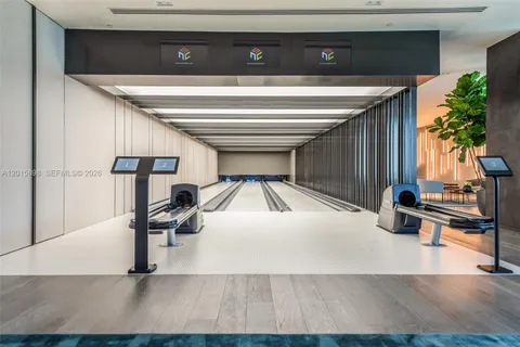 a room with wooden floor pool table and chairs