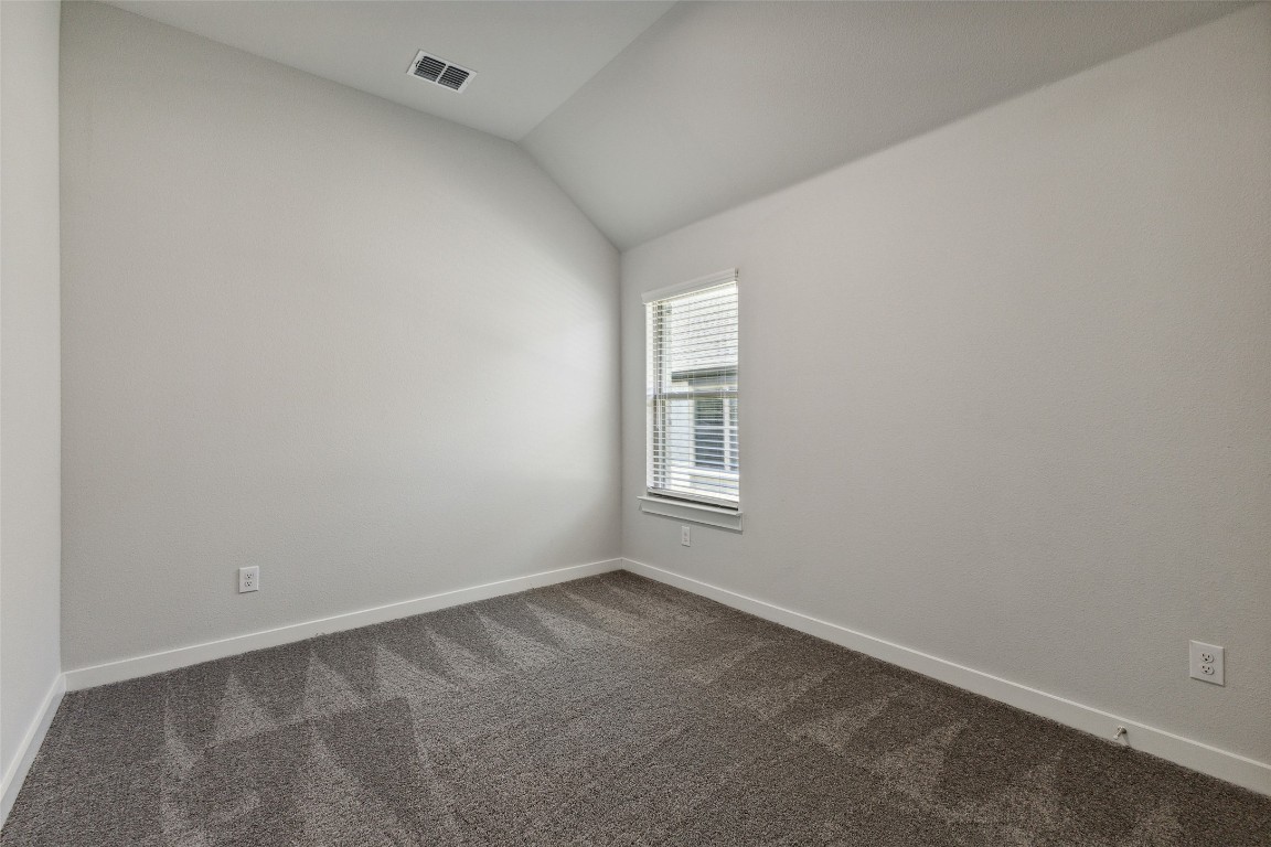 200 Hidalgo Lane Elgin, TX 78621 - Photo 14 of 25 Empty room with dark colored carpet, lofted ceiling, and baseboards