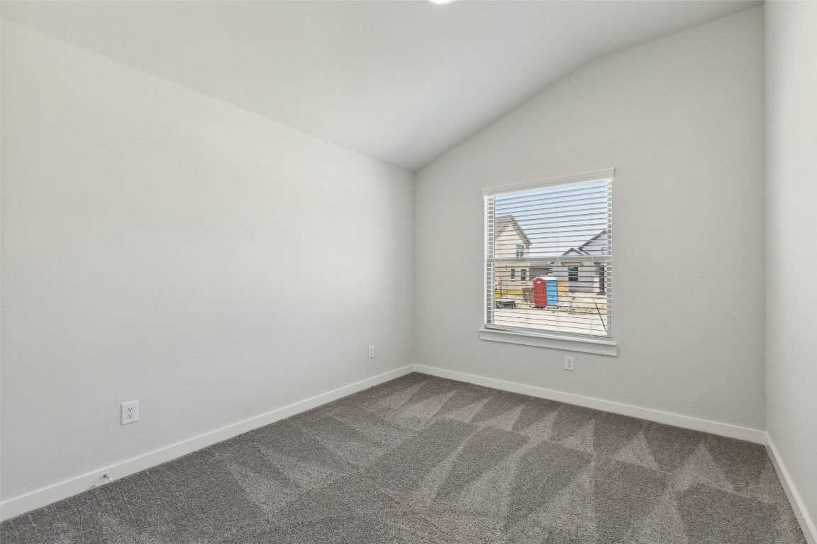 200 Hidalgo Lane Elgin, TX 78621 - Photo 15 of 25 Empty room with lofted ceiling, dark carpet, and baseboards