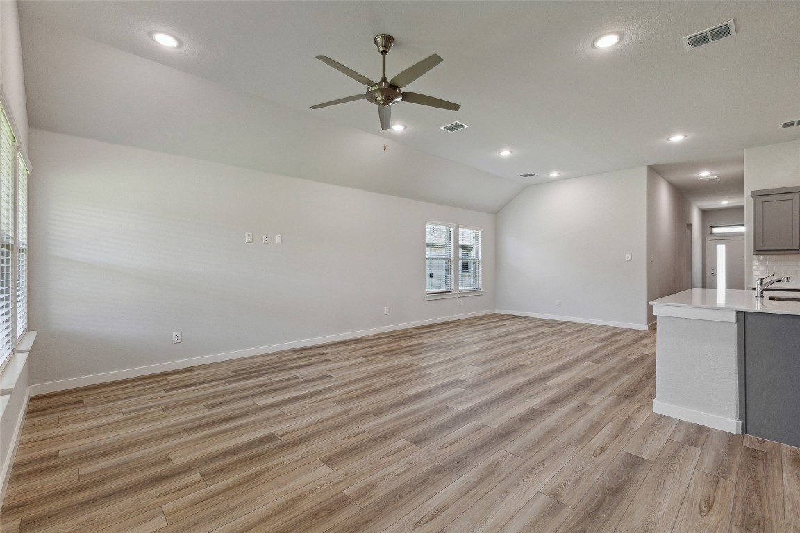 200 Hidalgo Lane Elgin, TX 78621 - Photo 5 of 25 Unfurnished living room with a ceiling fan, a sink, vaulted ceiling, light wood-style flooring, and baseboards