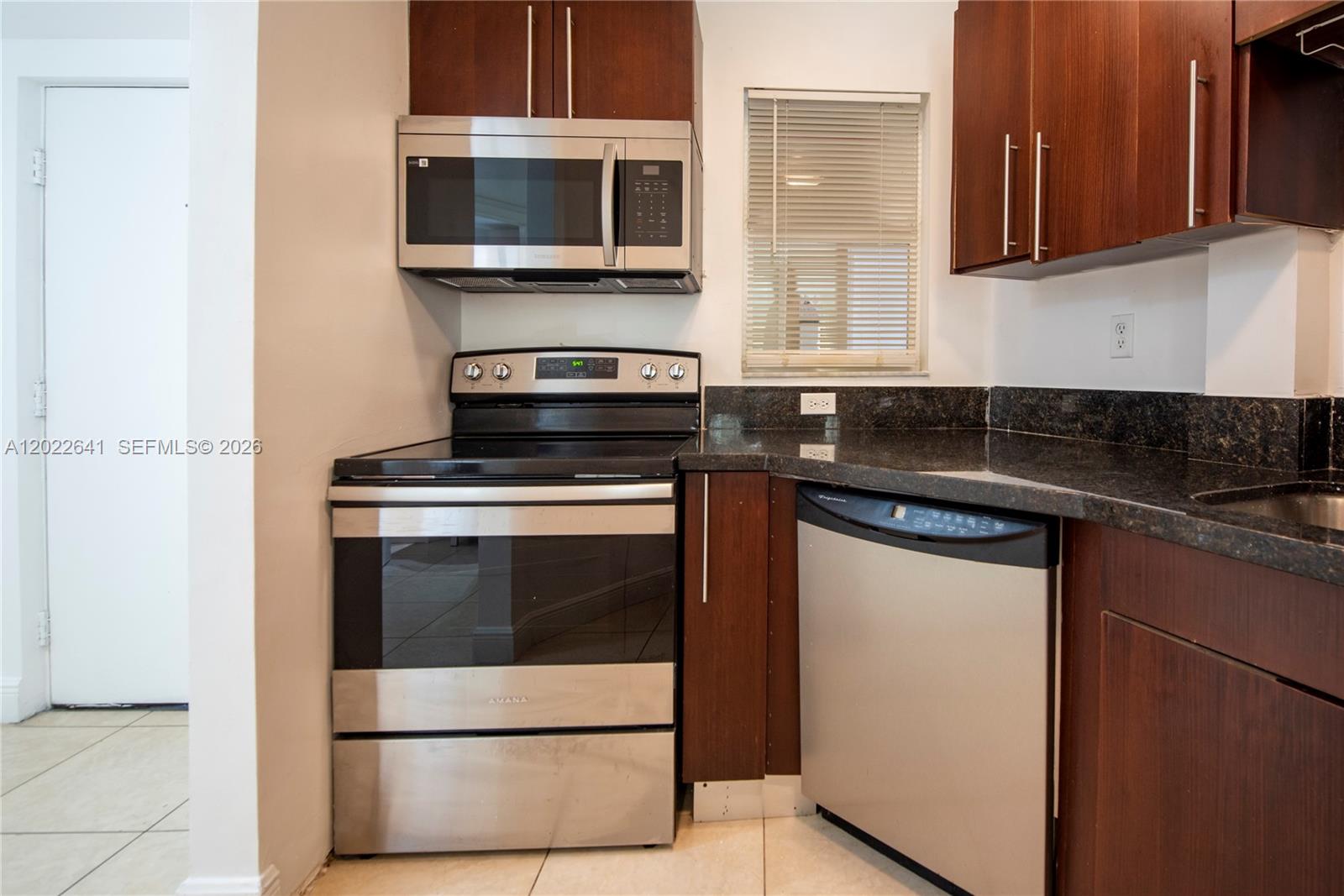 4147 Stirling Road, Unit 105 Dania Beach, FL 33314 - Photo 3 of 16 a kitchen with stainless steel appliances a stove microwave and sink