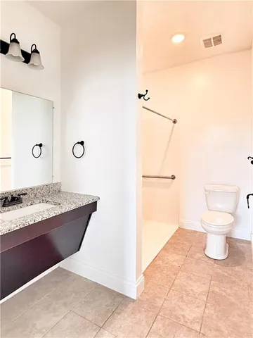 a bathroom with a granite countertop sink and a toilet