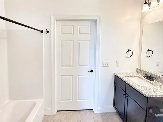 a bathroom with a granite countertop sink a mirror and a bathtub