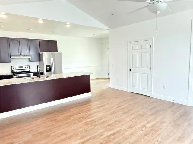 a large white kitchen with kitchen island a sink stainless steel appliances and cabinets