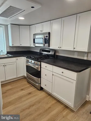 a kitchen with granite countertop white cabinets and black appliances