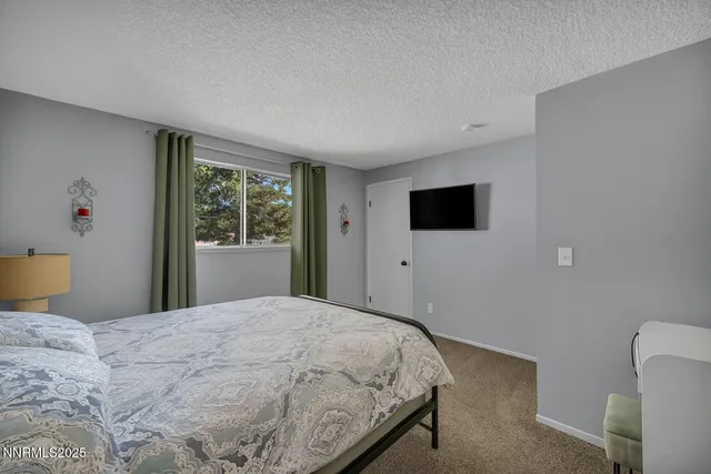 a bedroom with a bed tv and a window