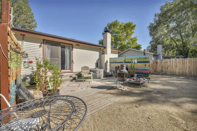 a view of a backyard with table and chairs under an umbrella with wooden fence