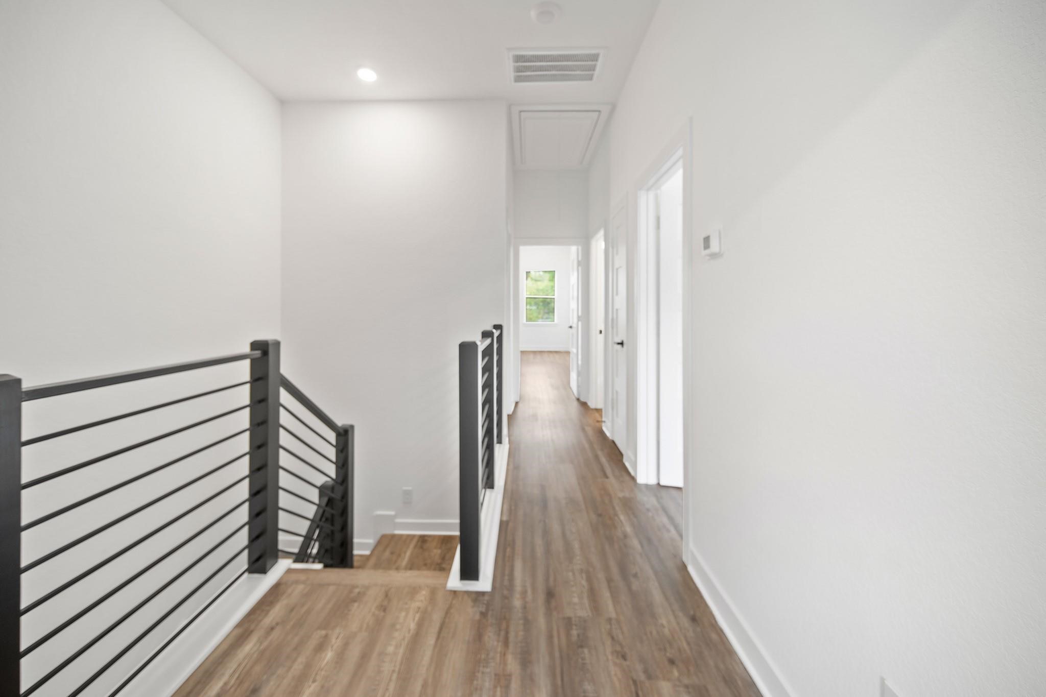 5813 England Street, Unit A Houston, TX 77021 - Photo 10 of 18 Bright and spacious hallway featuring sleek modern railings and beautiful hardwood flooring, leading to the upper-level rooms.