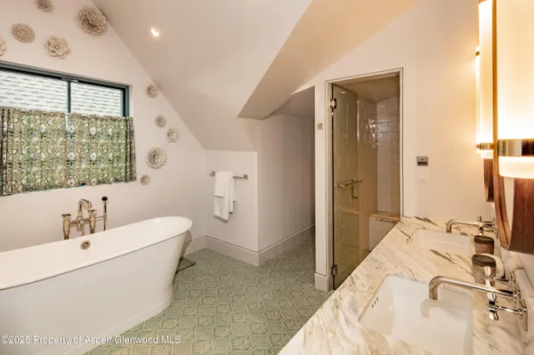 a en suite bathroom with a double vanity sink a mirror and a bathtub