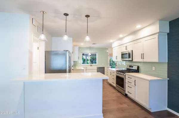 a large kitchen with stainless steel appliances granite countertop a stove a sink and a refrigerator